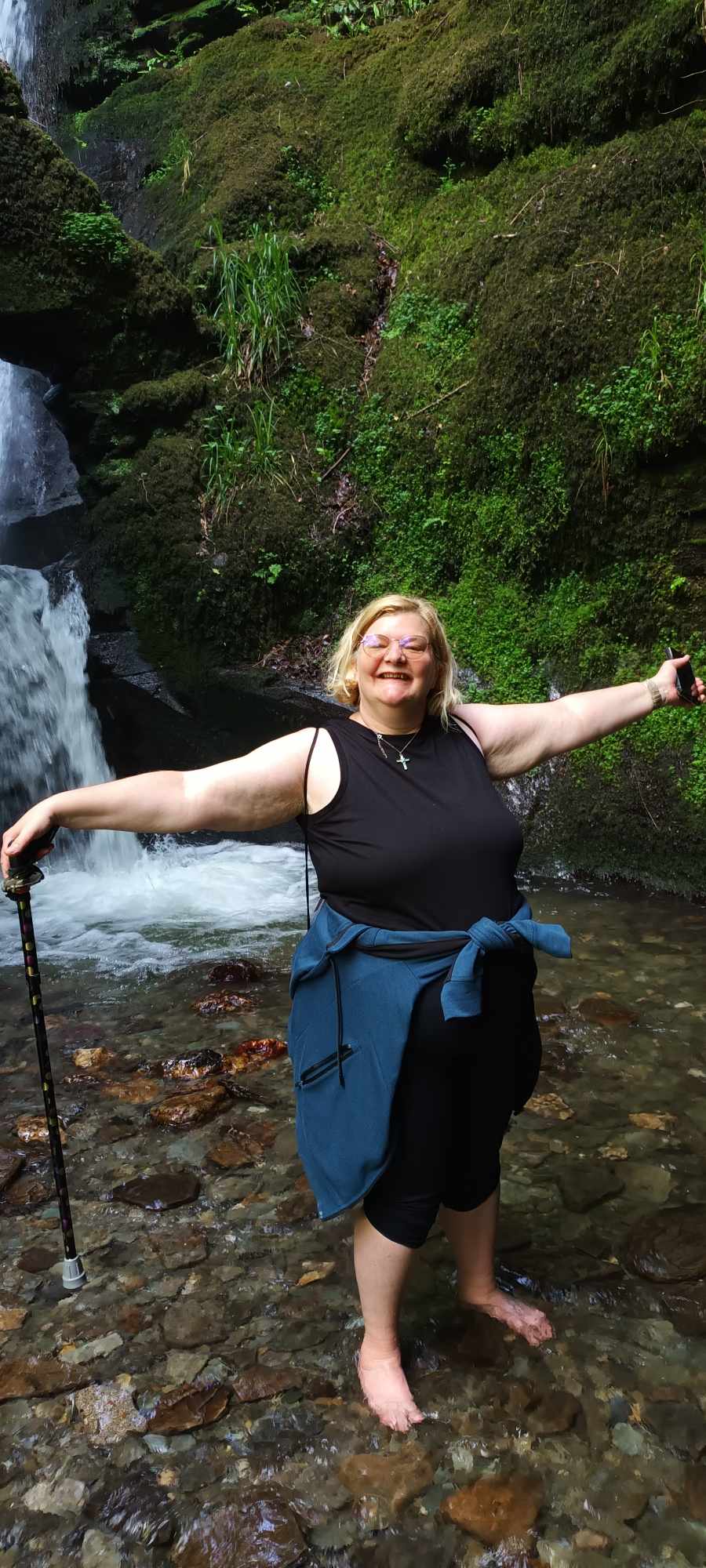 Paula Knott. In the background is a rocky hill and a waterfall.