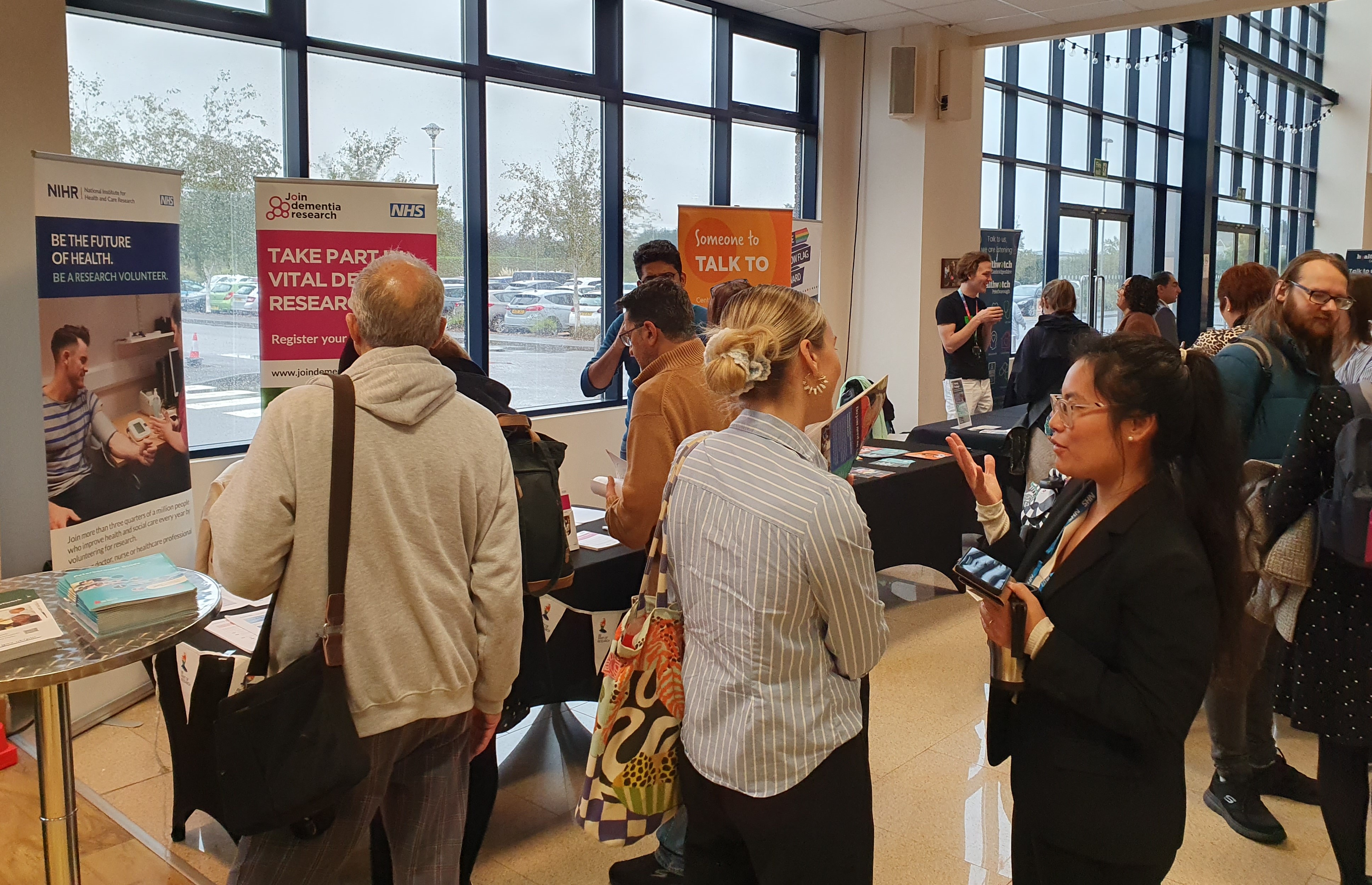 Delegates gather at the Summit event. People are talking to each other or visiting stands in the background.