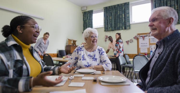 a photo of people laughing and smiling around a dinner table