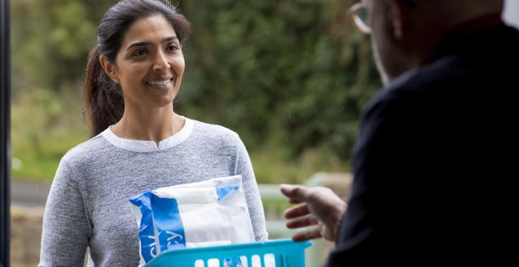 a woman smiling and talking to someone at their front door 