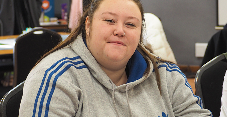 Young woman sat indoors looks at camera 