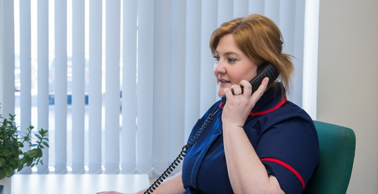 Nurse at palliative care hub taking a call on a landline 