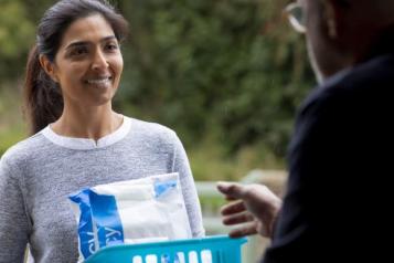 a woman smiling and talking to someone at their front door 