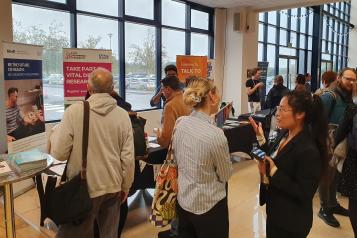 Delegates gather at the Summit event. People are talking to each other or visiting stands in the background.