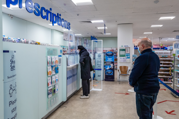 People queuing in a pharmacy to collect prescriptions